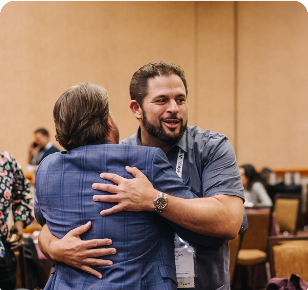 A man warmly hugging another person during a conference or event.