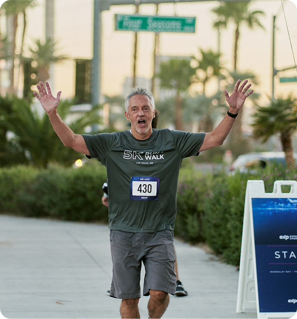 A man participating in a run, raising his arms in celebration.