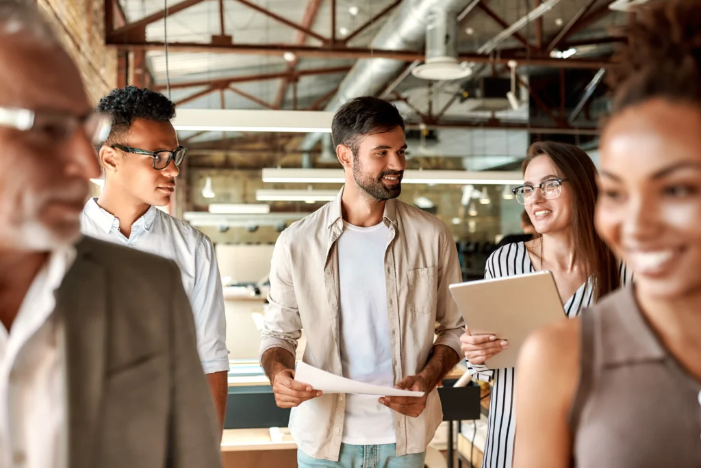 A group of colleagues in a modern office space, smiling and discussing documents, representing eXp Realty's referral network.