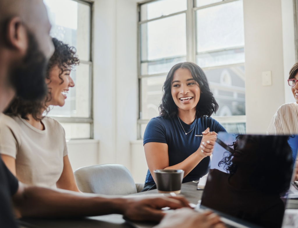 A diverse group of individuals collaborates around a table, engaging in a productive meeting setting.