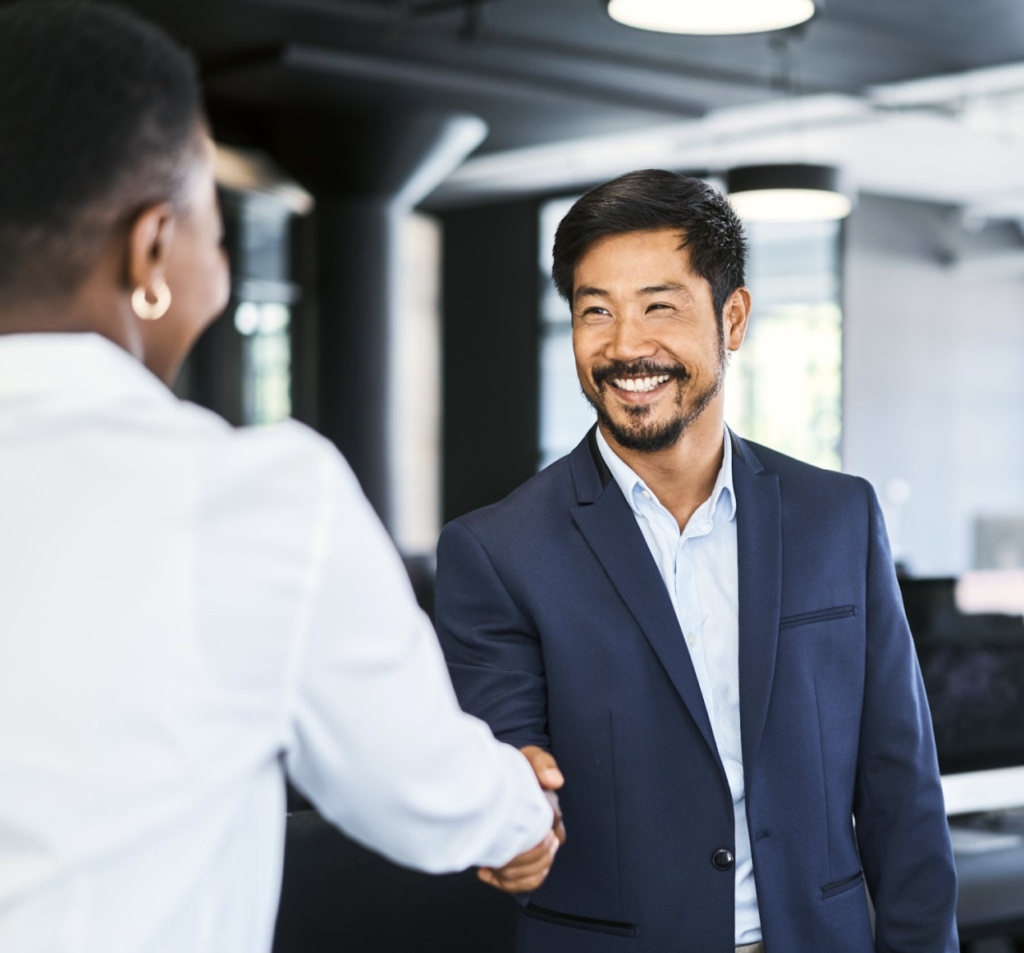 A man in a suit shakes hands with another man, symbolizing a professional agreement or greeting.